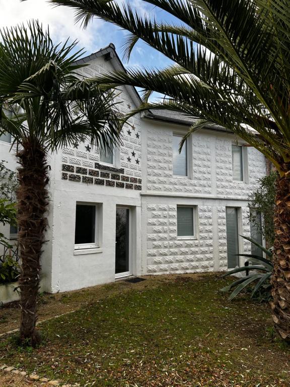 une maison blanche avec un palmier devant dans l'établissement MAISON à 100 METRES DE LA PLAGE, à Pléneuf-Val-André