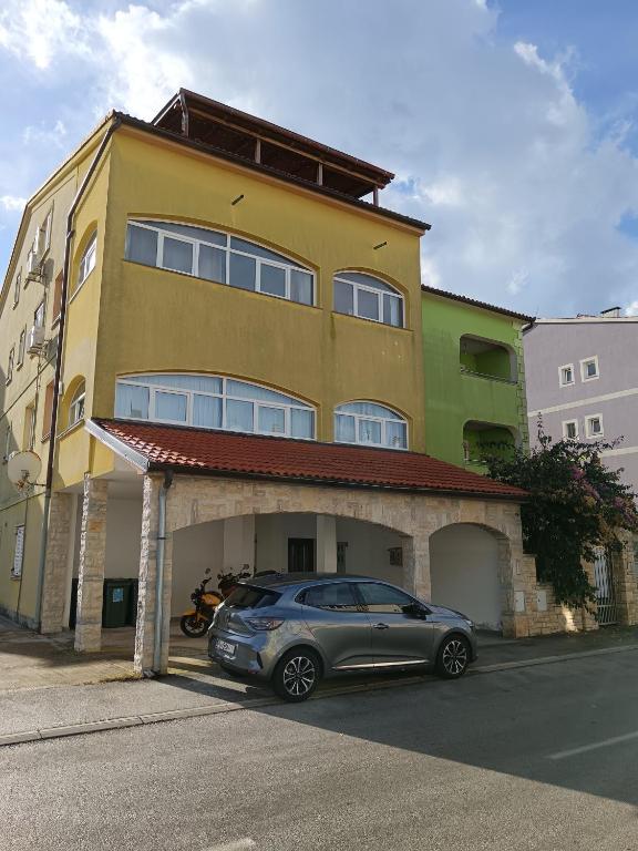 een auto geparkeerd voor een geel gebouw bij Pula,Gregovica in Pula