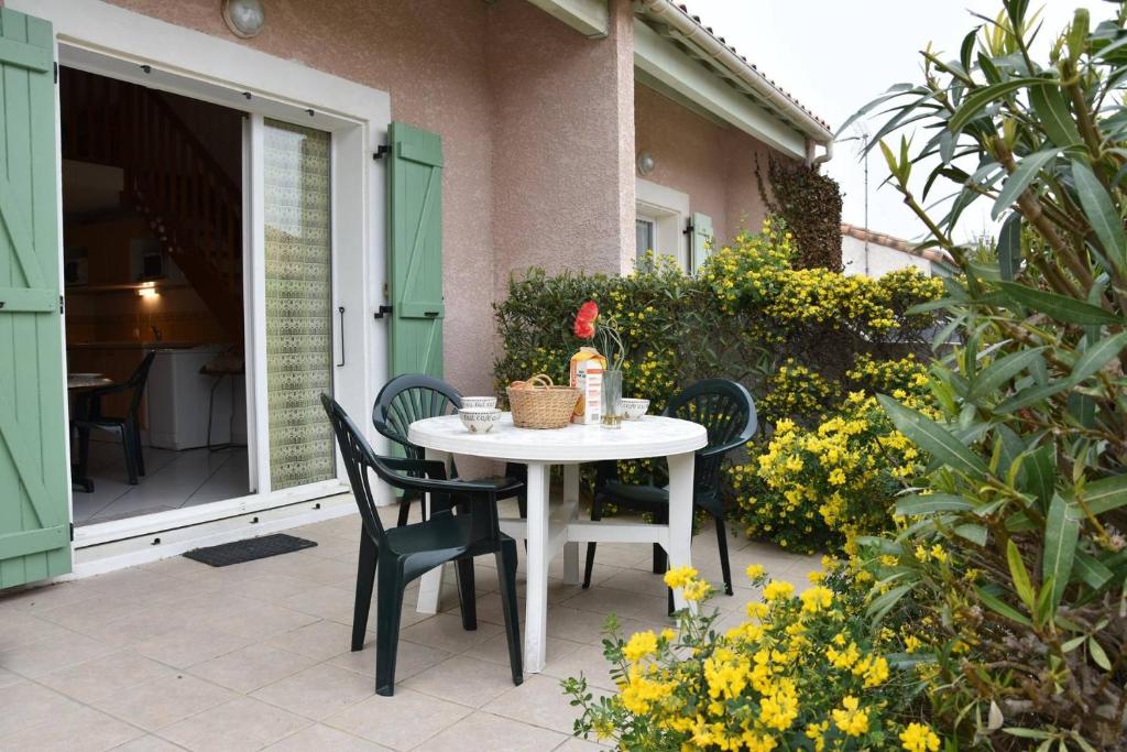 une table blanche et des chaises sur une terrasse dans l'établissement SP740-117 Maison 3 pièces mezzanine SAINT PIERRE LA MER, à Saint Pierre La Mer