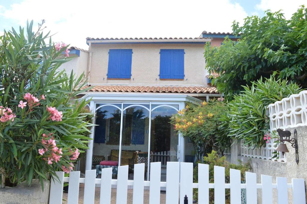 une clôture blanche devant une maison avec des volets bleus dans l'établissement SP720-010 Maison 4 pièces SAINT PIERRE LA MER, à Saint Pierre La Mer
