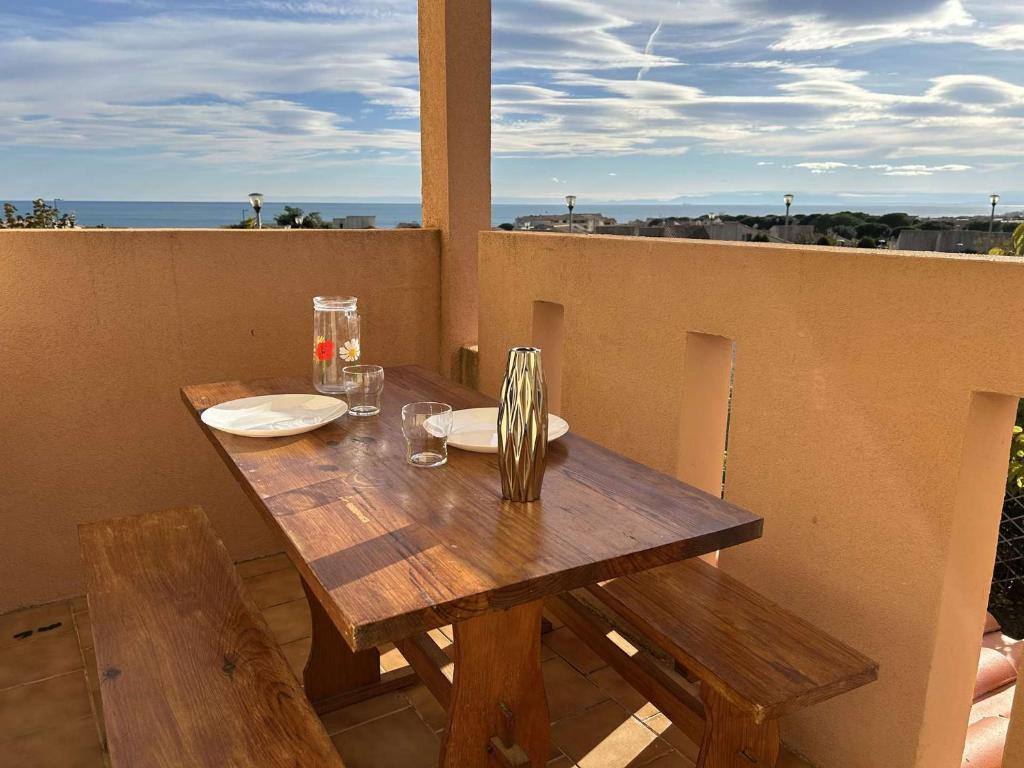 une table en bois avec des assiettes et des verres sur un balcon dans l'établissement SP520-C154 Appartement 2 pièces 4 couchages SAINT PIERRE LA MER, à Saint Pierre La Mer