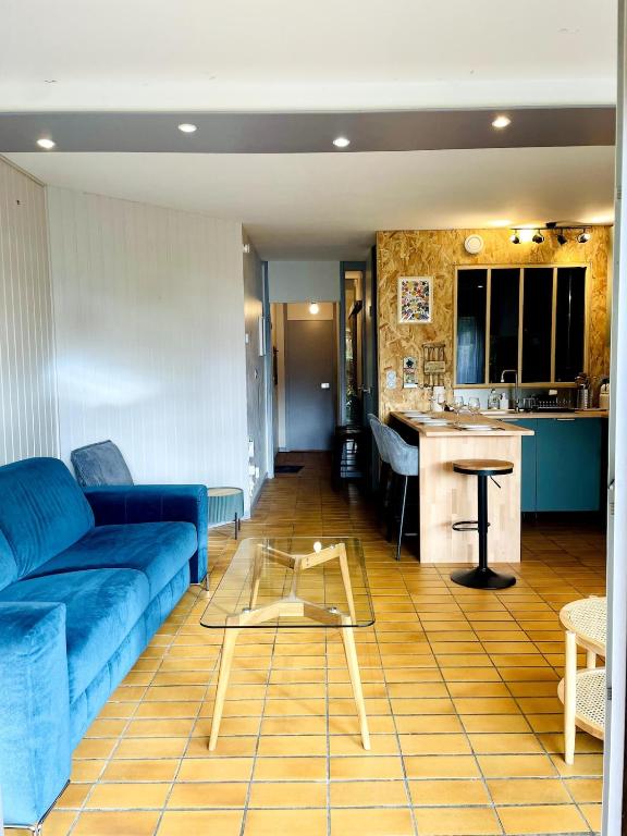 a living room with a blue couch and a kitchen at Le Mouette - Seaside in La Rochelle