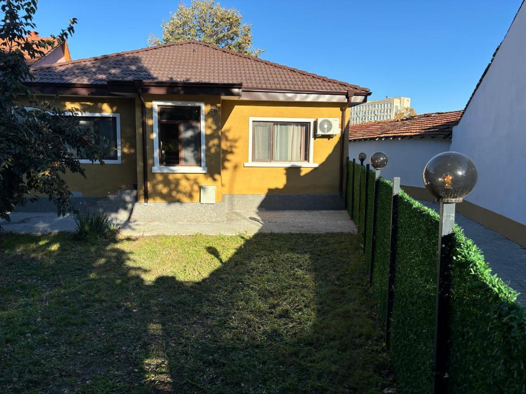 ein gelbes Haus mit einem Zaun davor in der Unterkunft Стаи за гости Георги Сава Раковски 97 in Targowischte