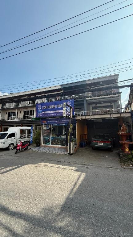 a parking lot with cars parked in front of a building at Chalong Paradise Guesthouse in Ban Bang Chak