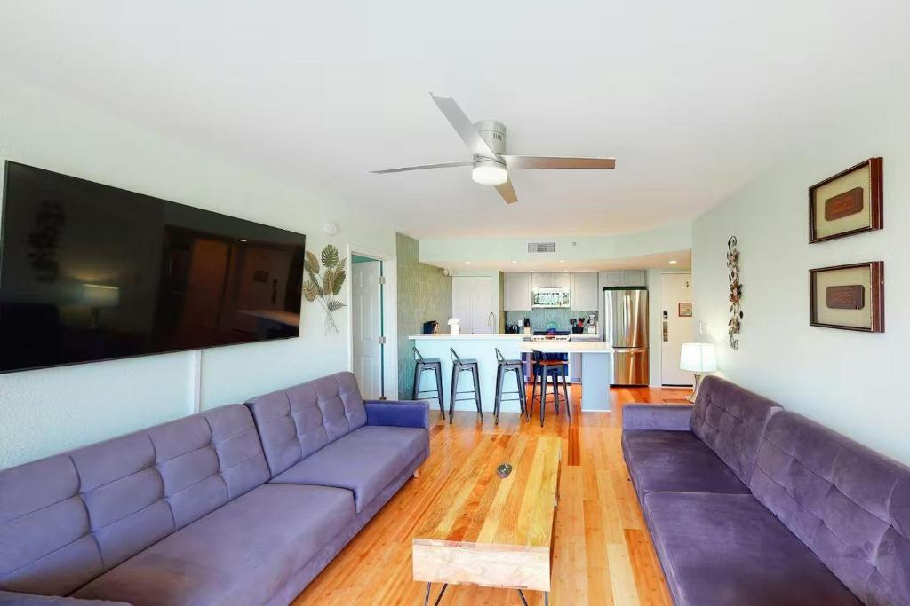 a living room with a purple couch and a kitchen at Cat Island Suite - Sunrise Suites in Key West