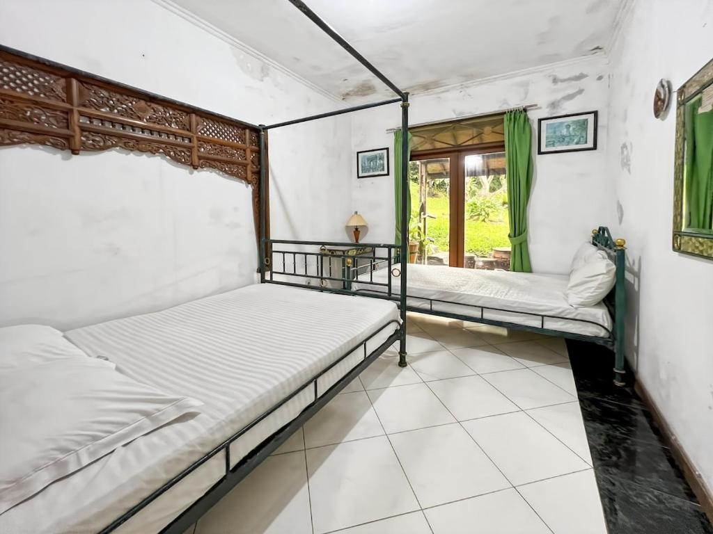 two beds in a room with a window at Large Bogor Villa with Pool, BBQ Grill & Fishing Spot by 2ndHome in Masing