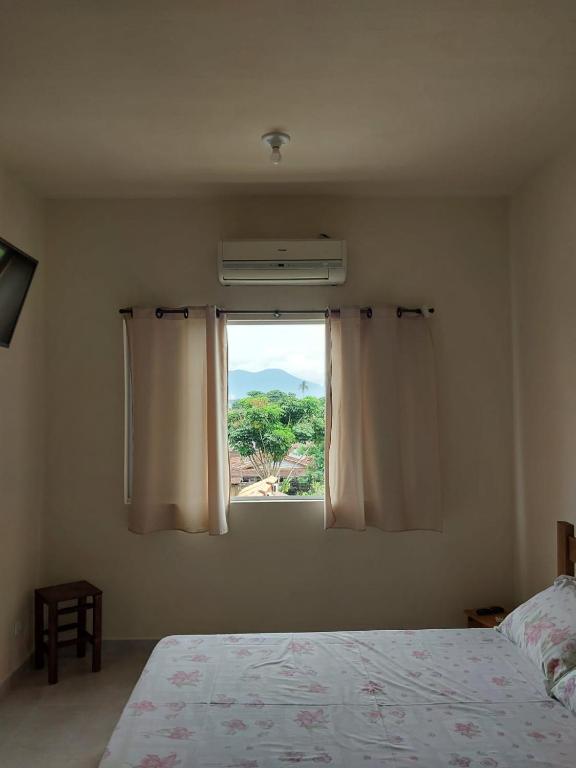 a bedroom with a bed and a window with a view at Suítes XIBAYKA in Ilhabela