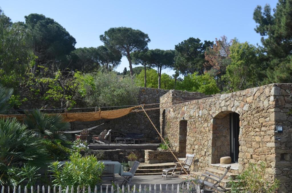 une maison en pierre avec une terrasse et des arbres dans l'établissement BergerieMuratinca privacy piscine vue mer 16 pers - location du samedi au samedi, à Corbara
