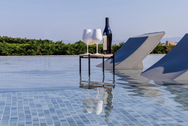 a table with two white chairs and a bottle of wine at Oikos Sani Suites in Sani Beach