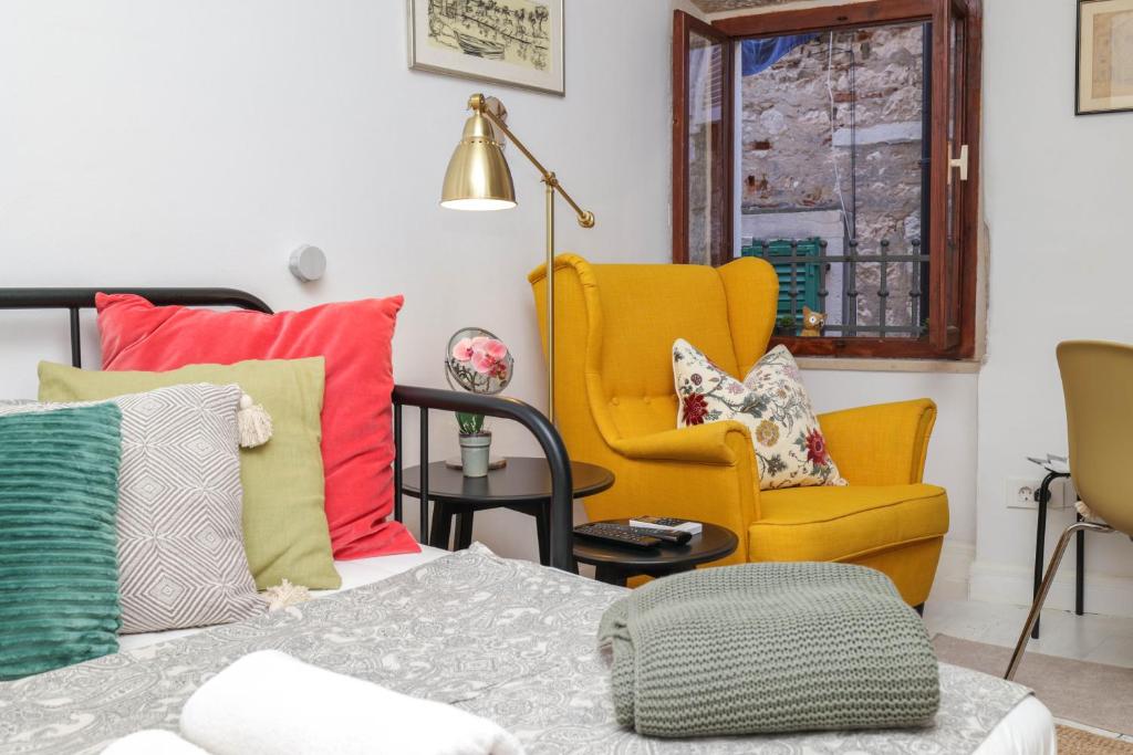 a room with a bed with colorful pillows and a chair at Studio Hedera in Rovinj