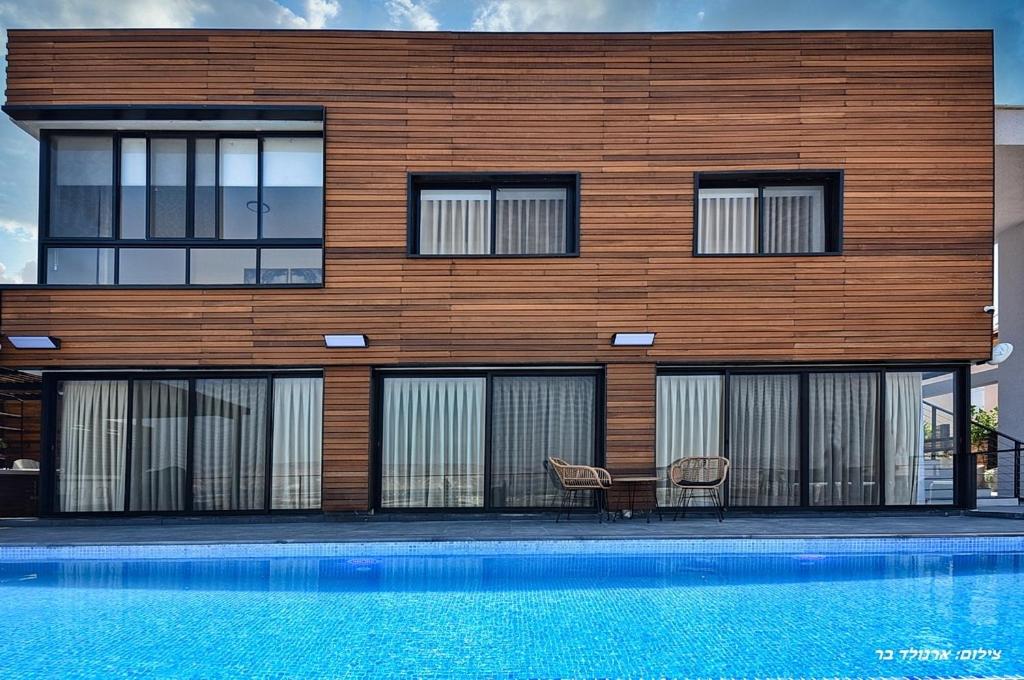 a building with a table and chairs next to a pool at אגמוניה in Menaẖemya