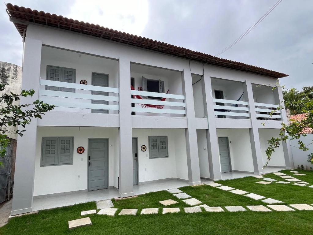 een wit huis met twee personen op het balkon bij RC FLAT Studio 05 Tamandaré, à 200m da praia in Tamandaré