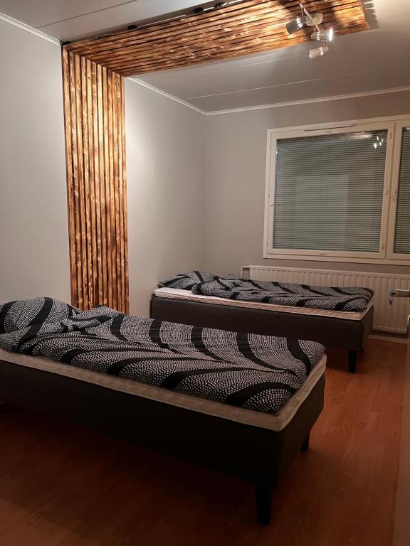 two beds sitting in a room with a window at Villa Northern Lights in Rovaniemi