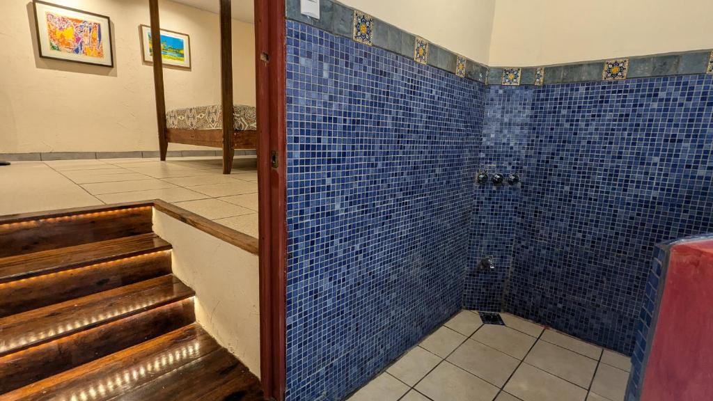 a bathroom with blue tiles on the wall and stairs at Tree House Beachfront Lodge in Puerto Viejo