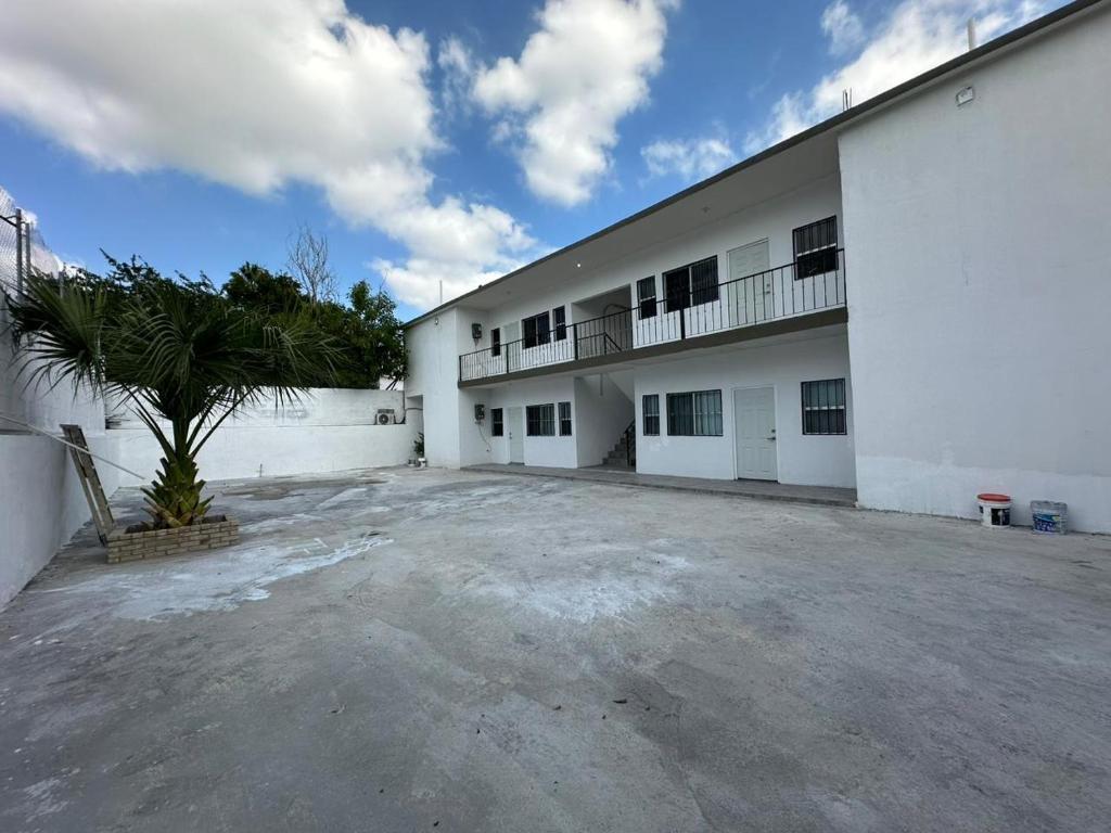 a large white building with a palm tree in front of it at Apartamentos la medero 4 in Nuevo Laredo