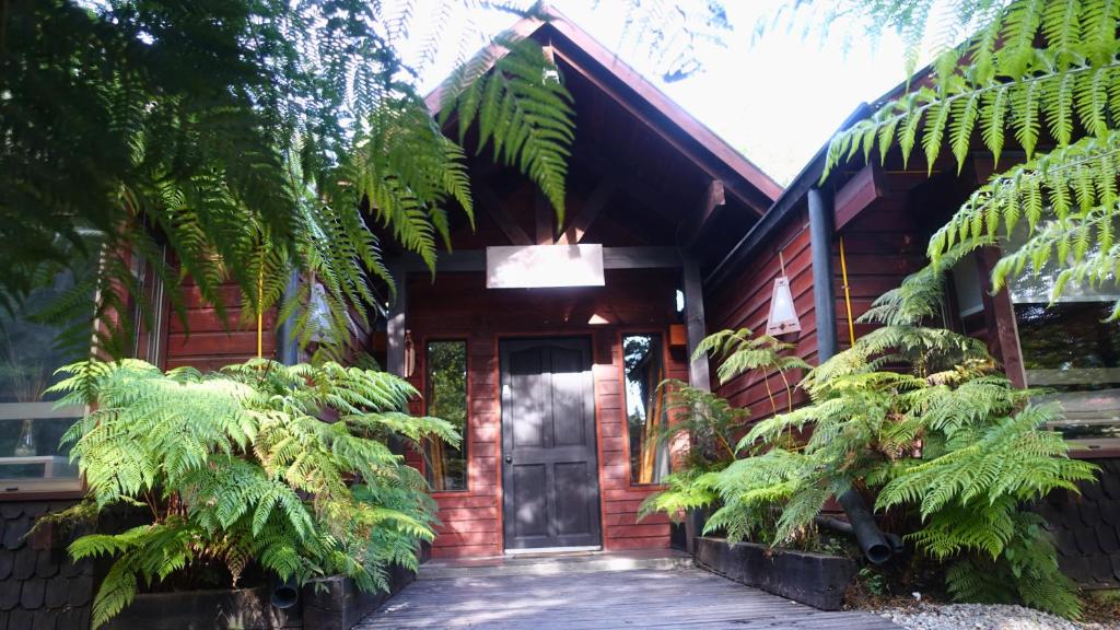 a red brick house with a door and some trees at Estero El Claro Hotel y Cabañas in Pucón