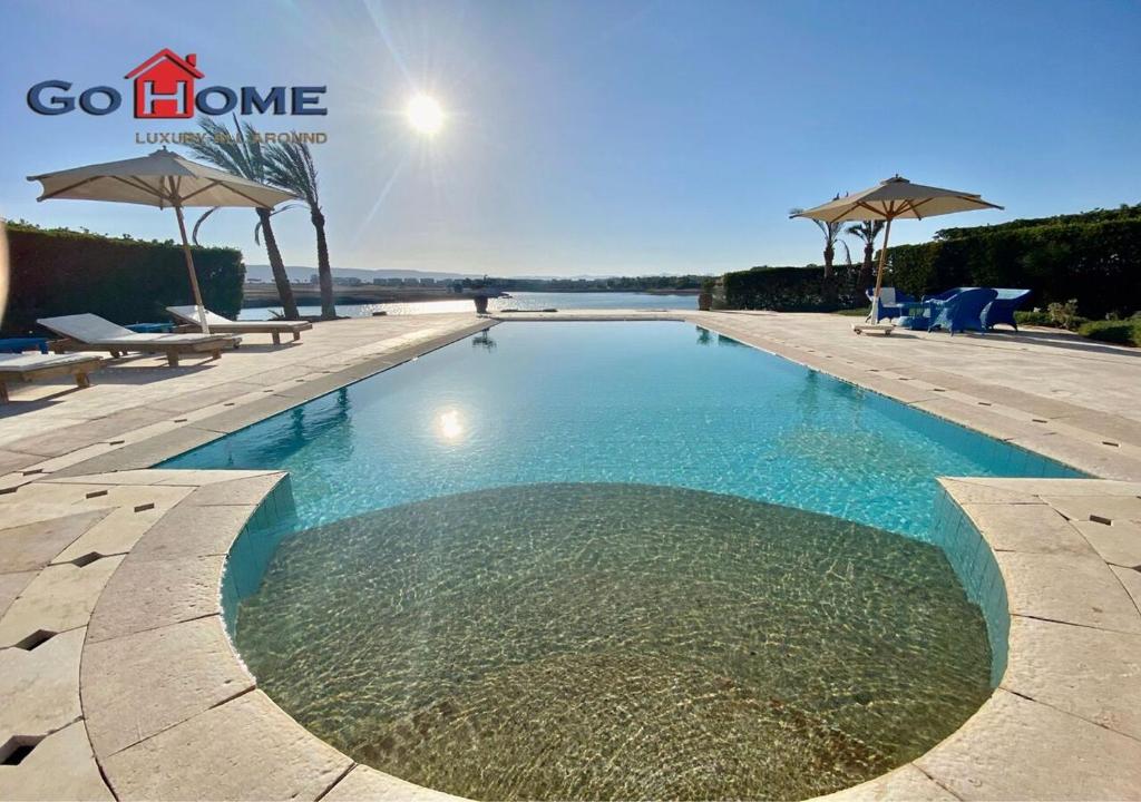a swimming pool with blue water and umbrellas at Stylish 4 BR with a Private Heated Pool V15 at White Villas in Hurghada