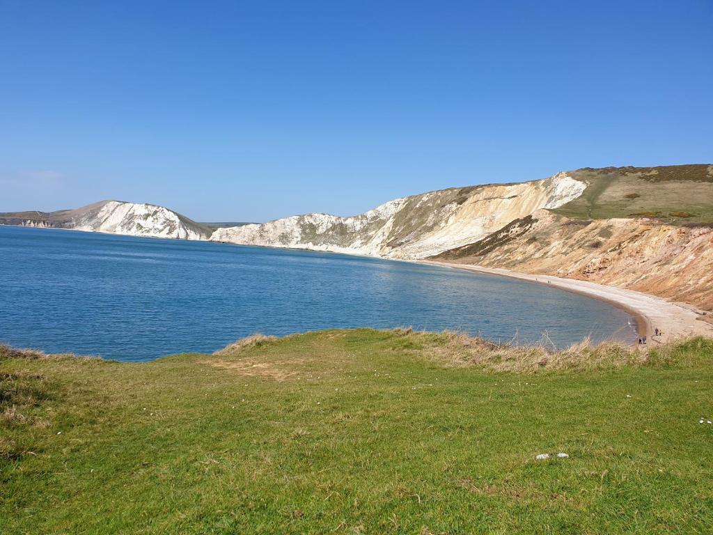 a beach with white cliffs and a body of water at HighTide - 2 bed with parking, balcony & sea view. in Swanage