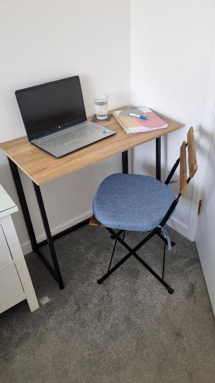 a desk with a laptop and a chair on it at HighTide - 2 bed with parking, balcony & sea view. in Swanage