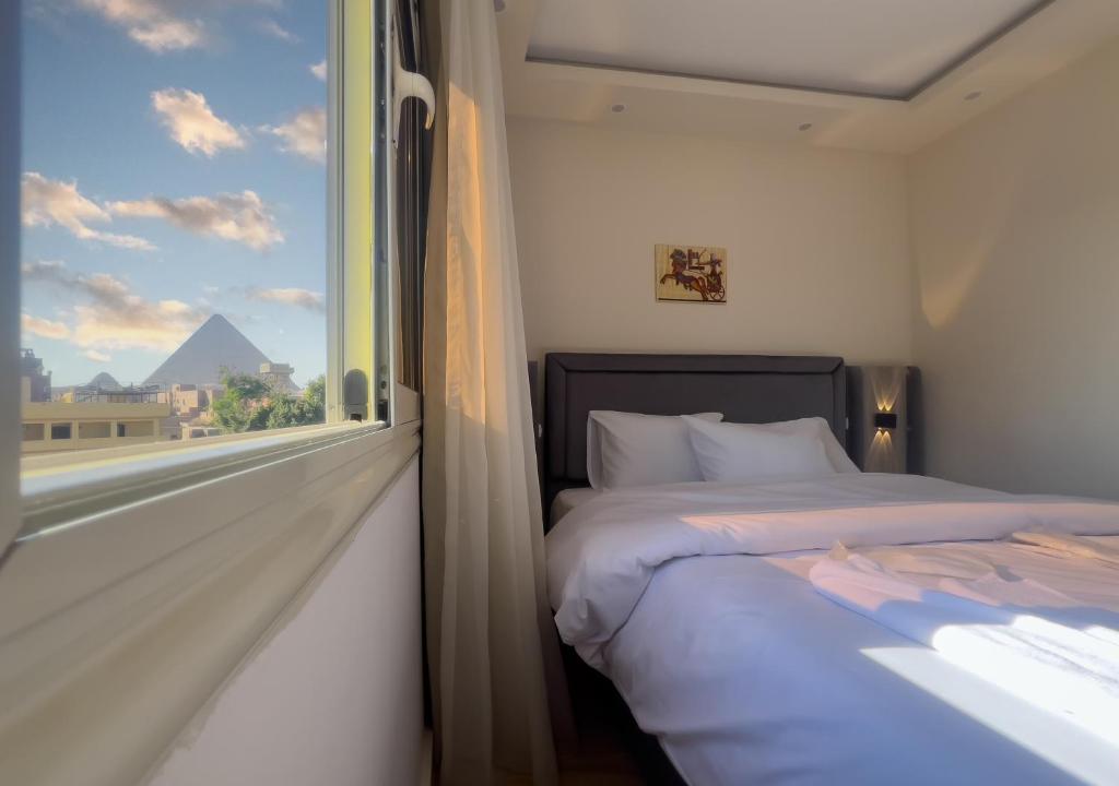 une chambre avec un lit et une fenêtre avec vue dans l'établissement Pyramids Art View Inn, au Caire
