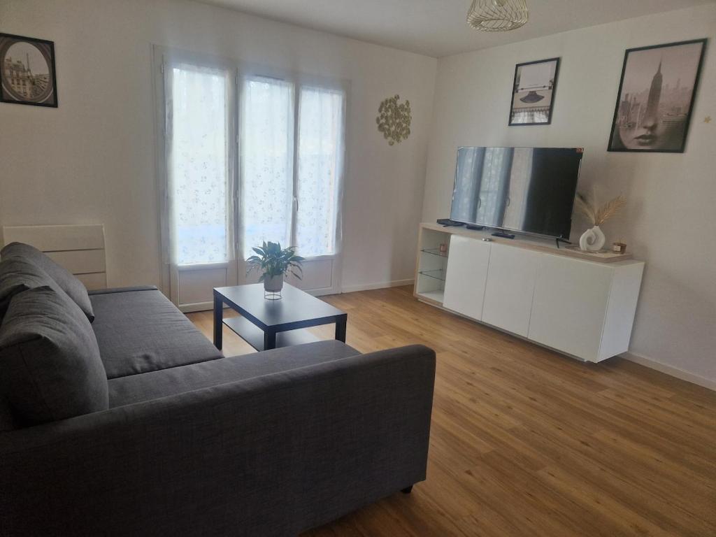 un salon avec un canapé et une télévision à écran plat dans l'établissement Charming Home, à Hérouville-Saint-Clair