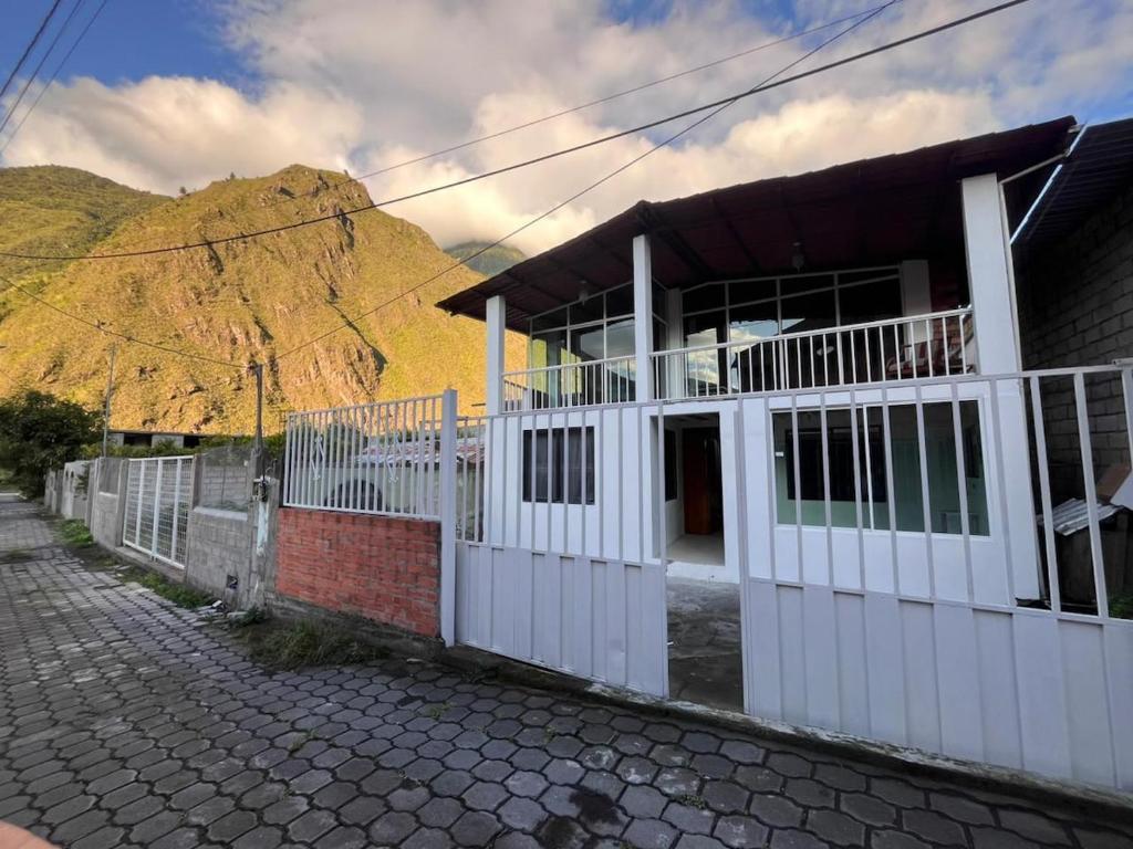 a house with a white fence in front of a mountain at Residencia Las Colinas in Juivi