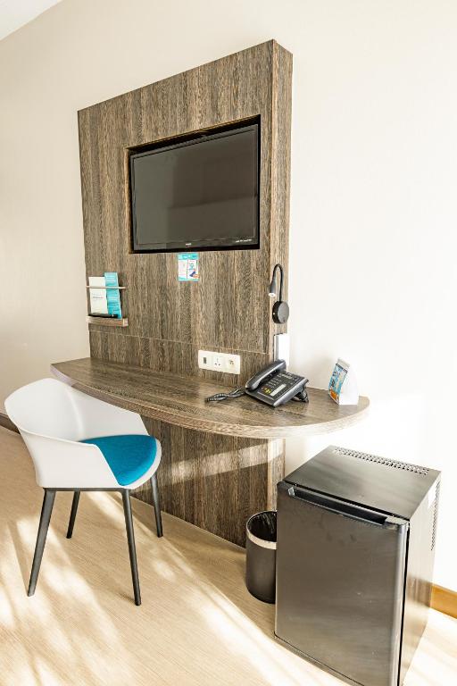 a living room with a tv and a chair and a table at Hotel Beaurivage in Noumea