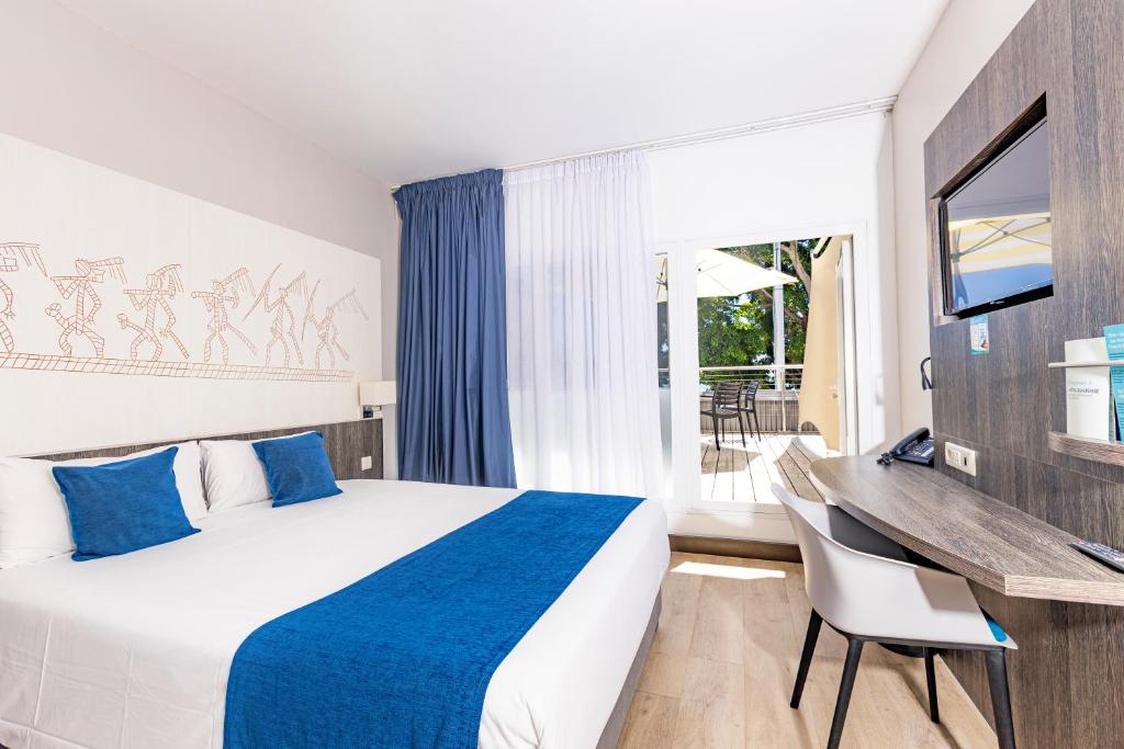 a hotel room with a bed and a desk and a window at Hotel Beaurivage in Noumea