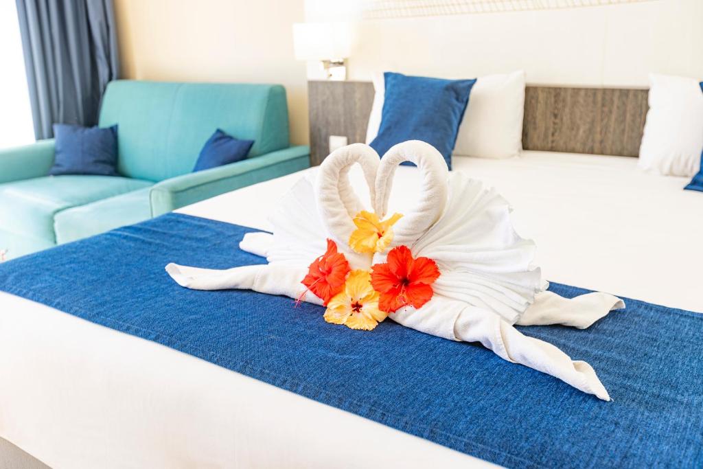a hotel room with a bed with a towel and flowers on it at Hotel Beaurivage in Noumea