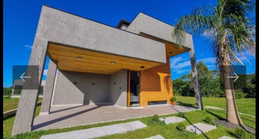 ein modernes Haus mit einer Palme davor in der Unterkunft Casa Completa Condomínio Rosa Internacional - ao lado Sufland - Garopaba-SC in Garopaba