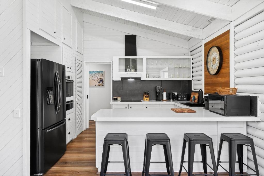 a kitchen with a black refrigerator and stools at Lonsdale By The Sea in Point Lonsdale