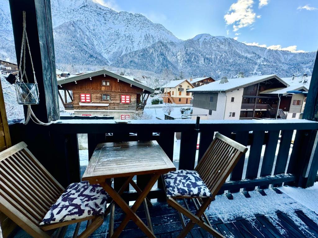 two chairs and a table on a balcony with snow covered mountains at Appartement vue Montblanc 5mn piste2 in Les Trabets
