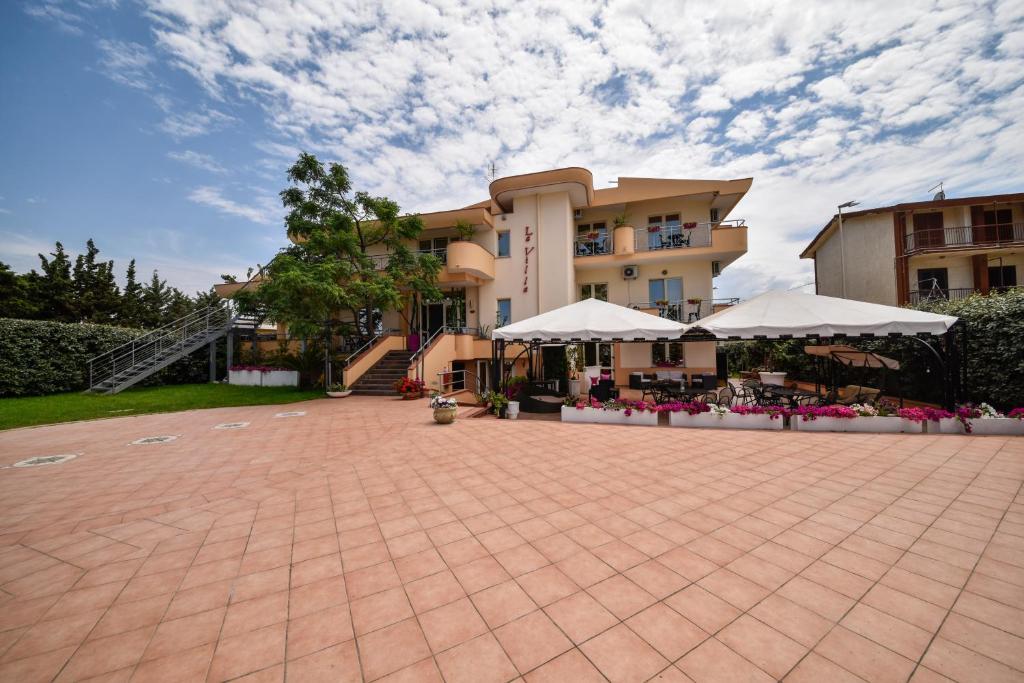 ein Gebäude mit weißen Sonnenschirmen im Innenhof in der Unterkunft Hotel La Villa in Corigliano Calabro