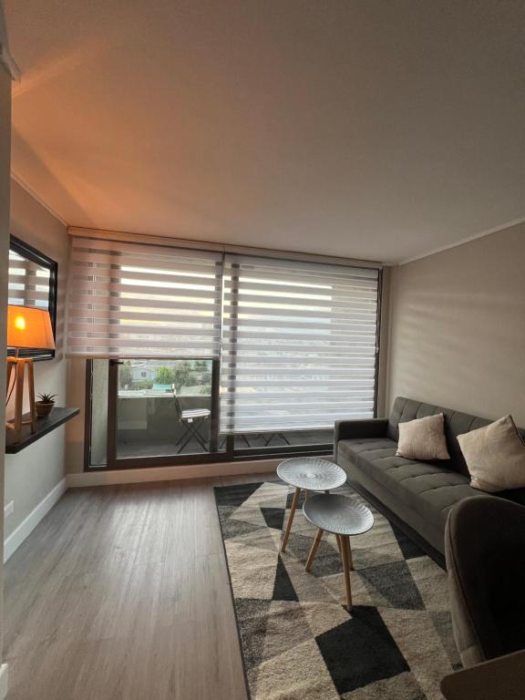 a living room with a couch and a large window at Moderno y cómodo departamento in Coquimbo