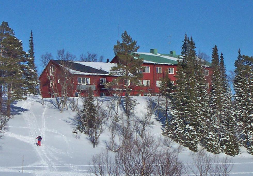 a person skiing down a snow covered slope in front of a building at Storliens Fjällgård in Storlien
