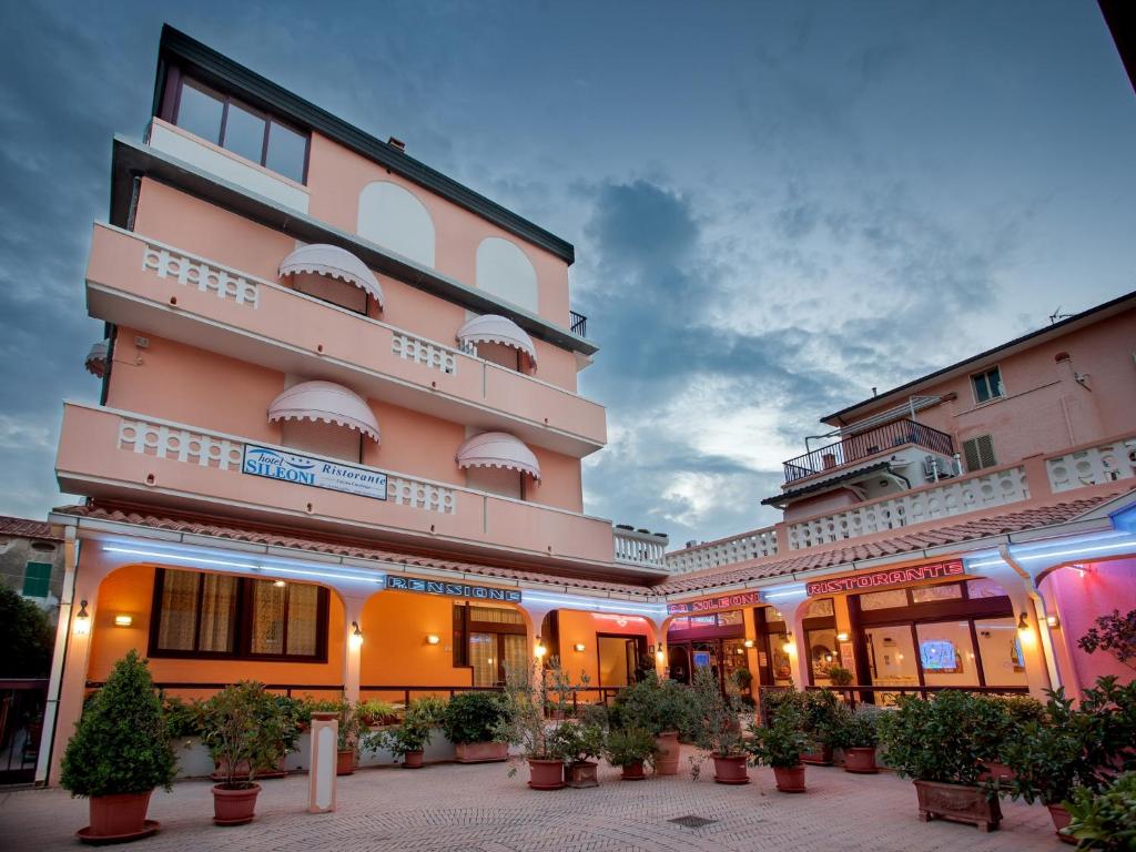 un grande edificio con piante in vaso di fronte ad esso di Hotel Sileoni a Marina di Cecina