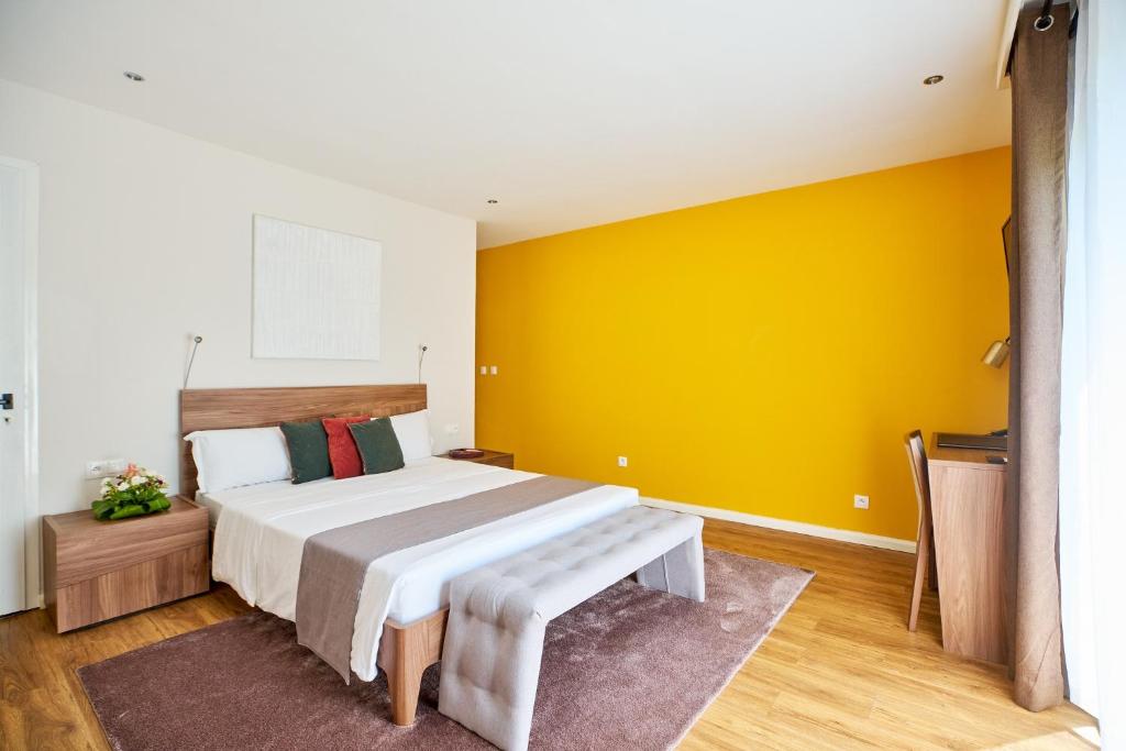 a bedroom with a large bed and a yellow wall at Roma Hôtel & Restaurant in Libreville