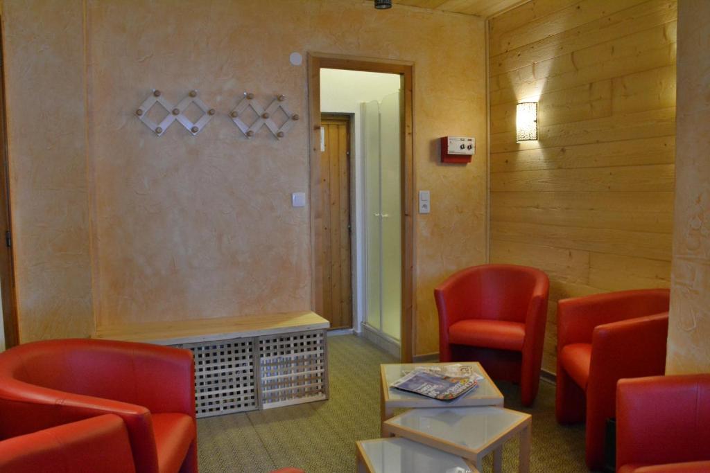 a waiting room with red chairs and a table at Hôtel Les Côtes, Résidence Loisirs et Chalets in Morzine