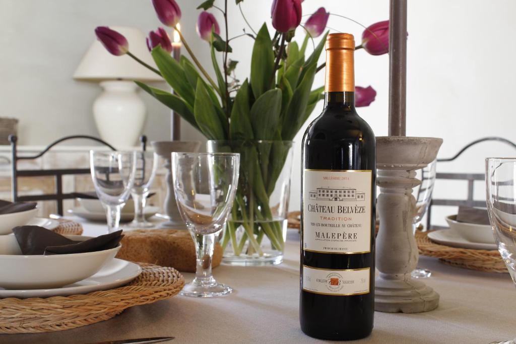 - une bouteille de vin assise sur une table avec des fleurs dans l'établissement Maison de Charme du Midi, à Carcassonne