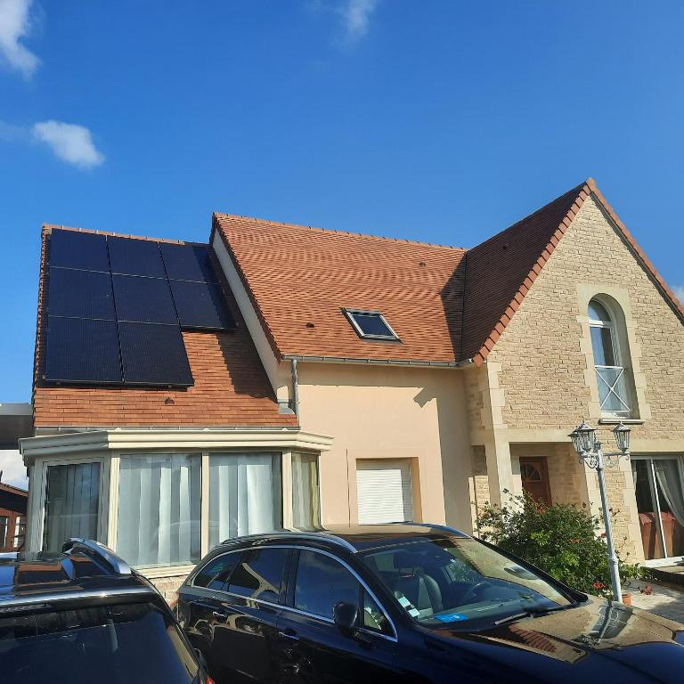 une maison avec des panneaux solaires sur le toit dans l'établissement courseullescommealamaison, à Courseulles-sur-Mer