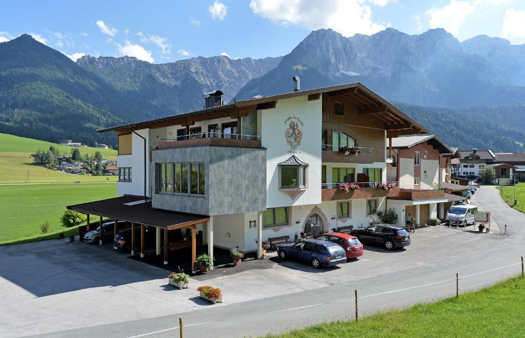 ein großes Gebäude mit Autos auf einem Parkplatz in der Unterkunft Hotel Garni Tirol in Walchsee