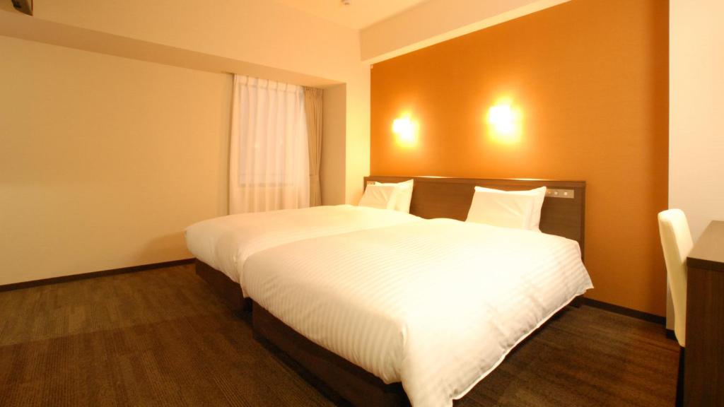 una camera da letto con un grande letto con lenzuola bianche di AB Hotel Kakamigahara a Kakamigahara
