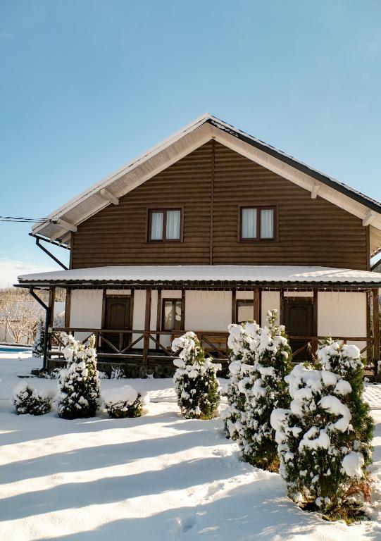 a house covered in snow with bushes in front of it at Мигово Гражда in Migovo