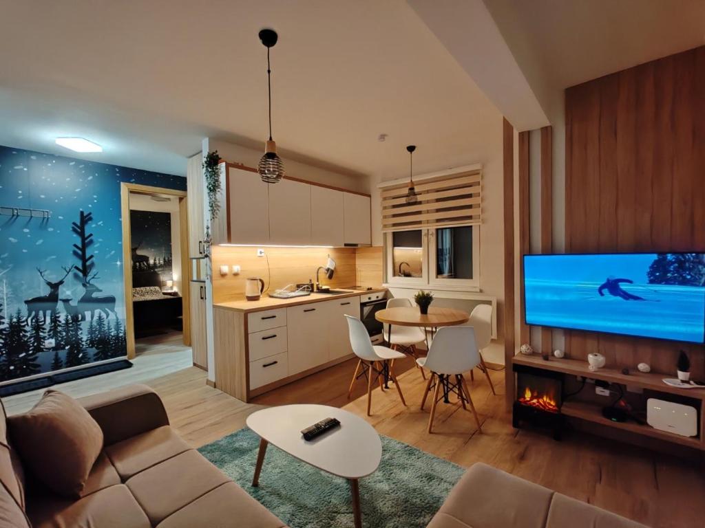 a living room with a couch and a tv and a kitchen at Mons Apartments Jahorina in Jahorina
