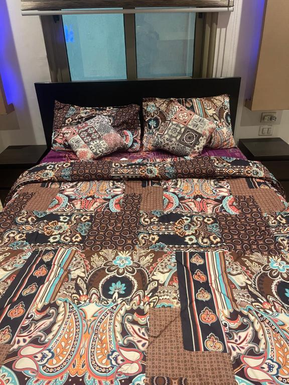 a bed with a colorful comforter and pillows on it at pyramids in ‘Ezbet `Abd el-Ḥamîd