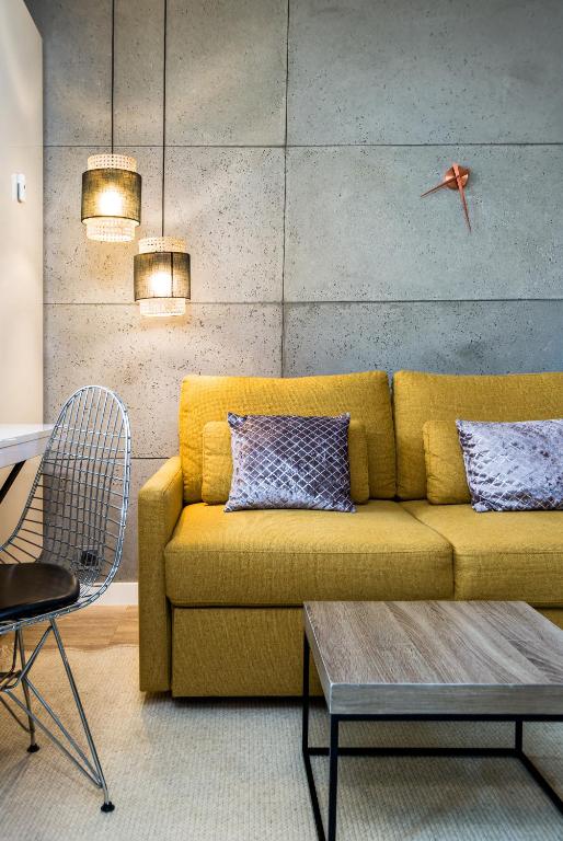 a living room with a yellow couch and a table at Kairos Apartments - Spodek - 100 m od Spodka in Katowice