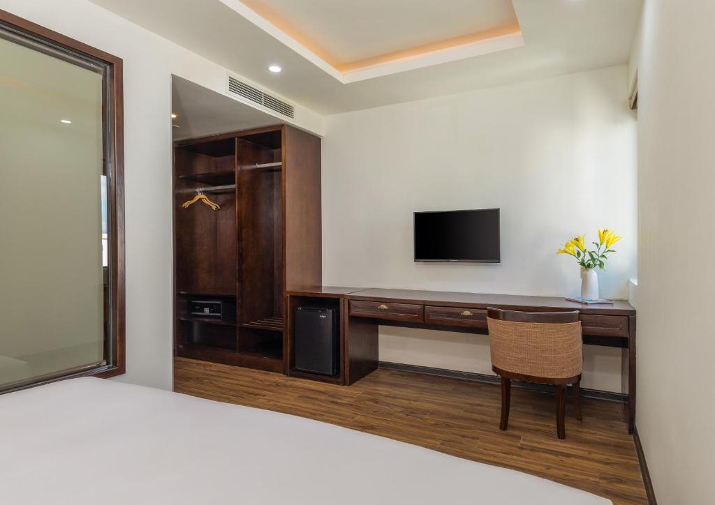 A built-in dressing and work area with a desk, TV, wardrobe, and mini-fridge.