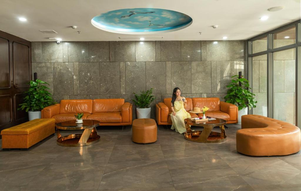 A polished lobby lounge with leather sofas, ottomans, plants, and a central coffee table.