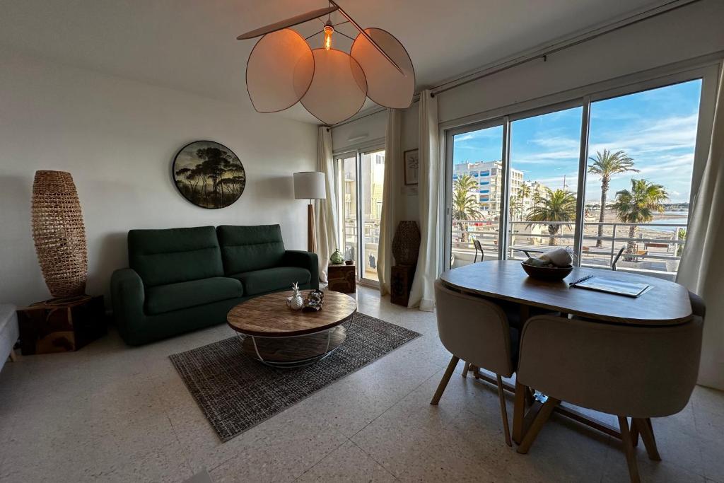 un salon avec un canapé vert et une table dans l'établissement L'Impérial 1- Appartement tout confort 1 chambre Vue mer, au Grau-du-Roi
