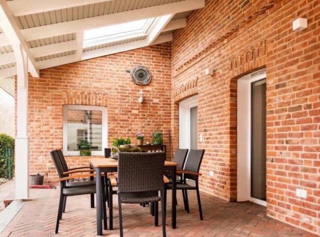 a patio with a table and chairs and a brick wall at Ferienhaus Alex - Wohnung im EG in Malliß